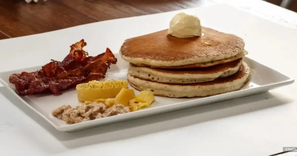 A close-up of a bk breakfast menu , with egg, cheese, and bacon, served with crispy hash browns and a coffee cup beside it.