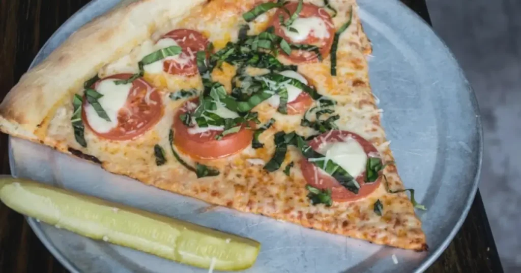 Overhead shot of Pickle Pie Pizza topped with tangy pickles, melted cheese, and fresh dill on a golden crust, sliced and ready to serve